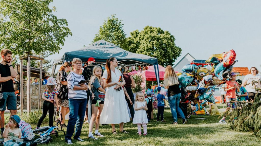A lively outdoor gathering with families enjoying balloons and a sunny day.